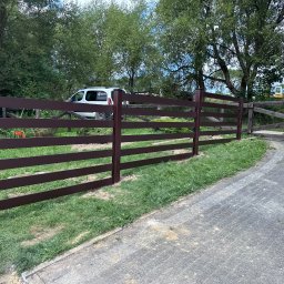 SEMAX Andrzej Sech - Nowoczesne, poziome ogrodzenie panelowe w kolorze brązowym, z widoczną bramą w tle i firmowym vanem. Estetyczne wykończenie posesji.