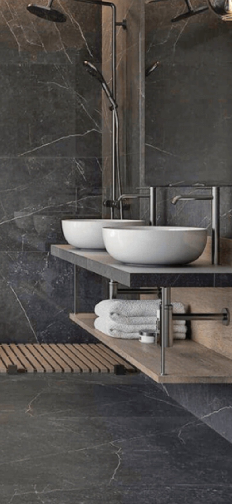 Nowoczesna łazienka z ciemnymi marmurowymi płytkami, dwiema okrągłymi umywalkami nablatowymi, minimalistyczną armaturą w kolorze czarnym, drewnianą półką z ręcznikami i drewnianą kratką...