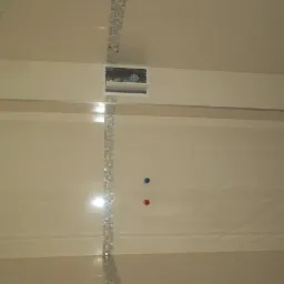 Wykończona łazienka z beżowymi płytkami, dekoracyjnym pasem mozaiki i podwieszanym sufitem z otworem inspekcyjnym.