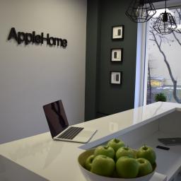 AppleHome - serwis Apple Warszawa serwis iPhone - Recepcja firmy z laptopem i misą zielonych jabłek na blacie, na ścianie logo firmy AppleHome i zdjęcia telefonów w ramkach