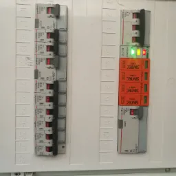 Rozdzielnica elektryczna z bezpiecznikami i modułami ochronnymi, widoczne oznaczenia Legrand i Simtec, numery obwodów od 1 do 28.