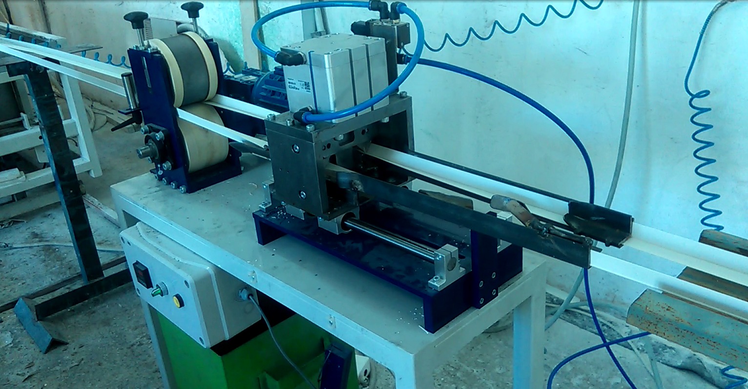 Maszyna do obróbki profili z tworzyw sztucznych na stanowisku pracy, widoczne elementy pneumatyczne i sterujące.