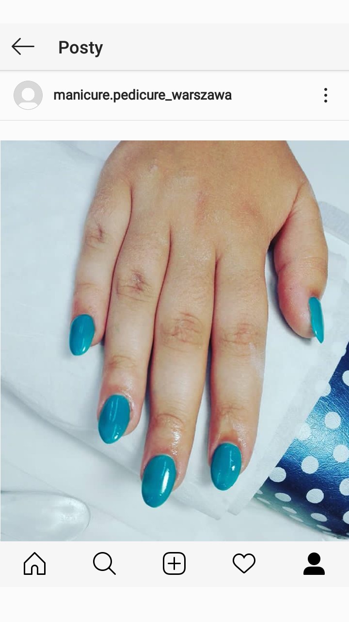 Dłoń z pomalowanymi na turkusowo owalnymi paznokciami, ułożona na białym podkładzie z fragmentem niebieskiej podkładki w białe kropki w prawym dolnym rogu.