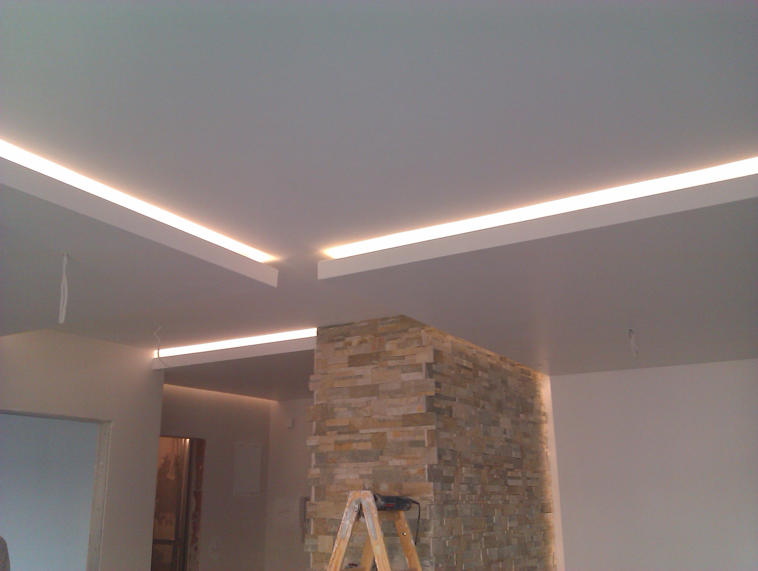 Nowoczesny sufit podwieszany z oświetleniem LED w aranżacji wnętrza, widoczna ściana z dekoracyjnej cegły i drabina malarska