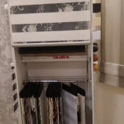 Ekspozycja różnych wzorów i kolorów rolet okiennych w salonie, z widocznym logo Eurofirany na górnej rolecie.