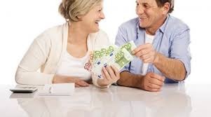 Uśmiechnięta para trzymająca wachlarz banknotów euro na białym tle, obok kalkulator i zwitek papieru.