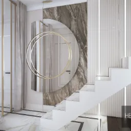 Nowoczesne wnętrze domu z białymi schodami, marmurową podłogą i ścianą z dekoracyjnym lustrem w kształcie okręgu, oświetlonym złotymi lampami. Widoczny fragment szklanej ściany z złotymi ramami...