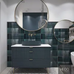 Wizualizacja łazienki z umywalką nablatową w kolorze ciemnego granatu, szafką z frezowanymi frontami i złotymi nóżkami, okrągłymi lustrami w złotych ramach oraz ścianą wyłożoną ciemnozielonymi...