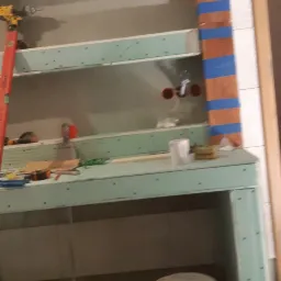 Stelaż z płyty karton gips z widocznymi profilami, otwory na instalacje, narzędzia i puszki farby, przygotowany do dalszych prac wykończeniowych.