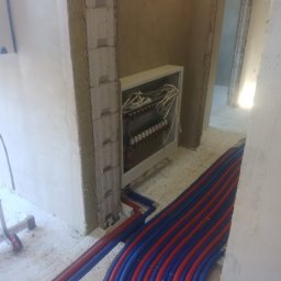 F.U.H Sanitec - Rozłożone rury ogrzewania podłogowego w kolorze niebieskim i czerwonym, prowadzące do rozdzielacza w Skarszewach. Widok na surowy stan wykończenia.