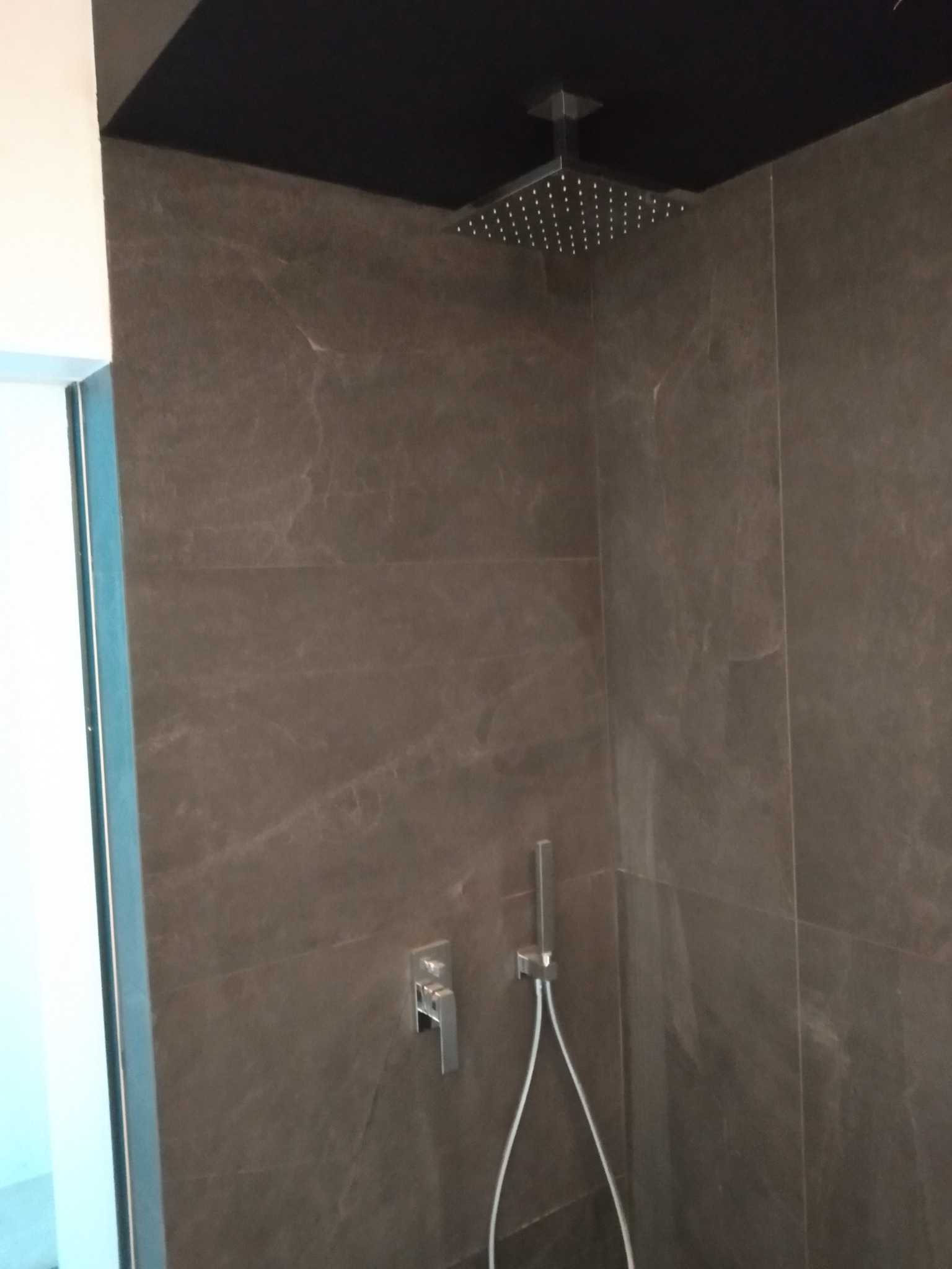 Nowoczesna kabina prysznicowa z deszczownicą i szarobrązowymi płytkami imitującymi marmur w Jastrzębiu-Zdroju.