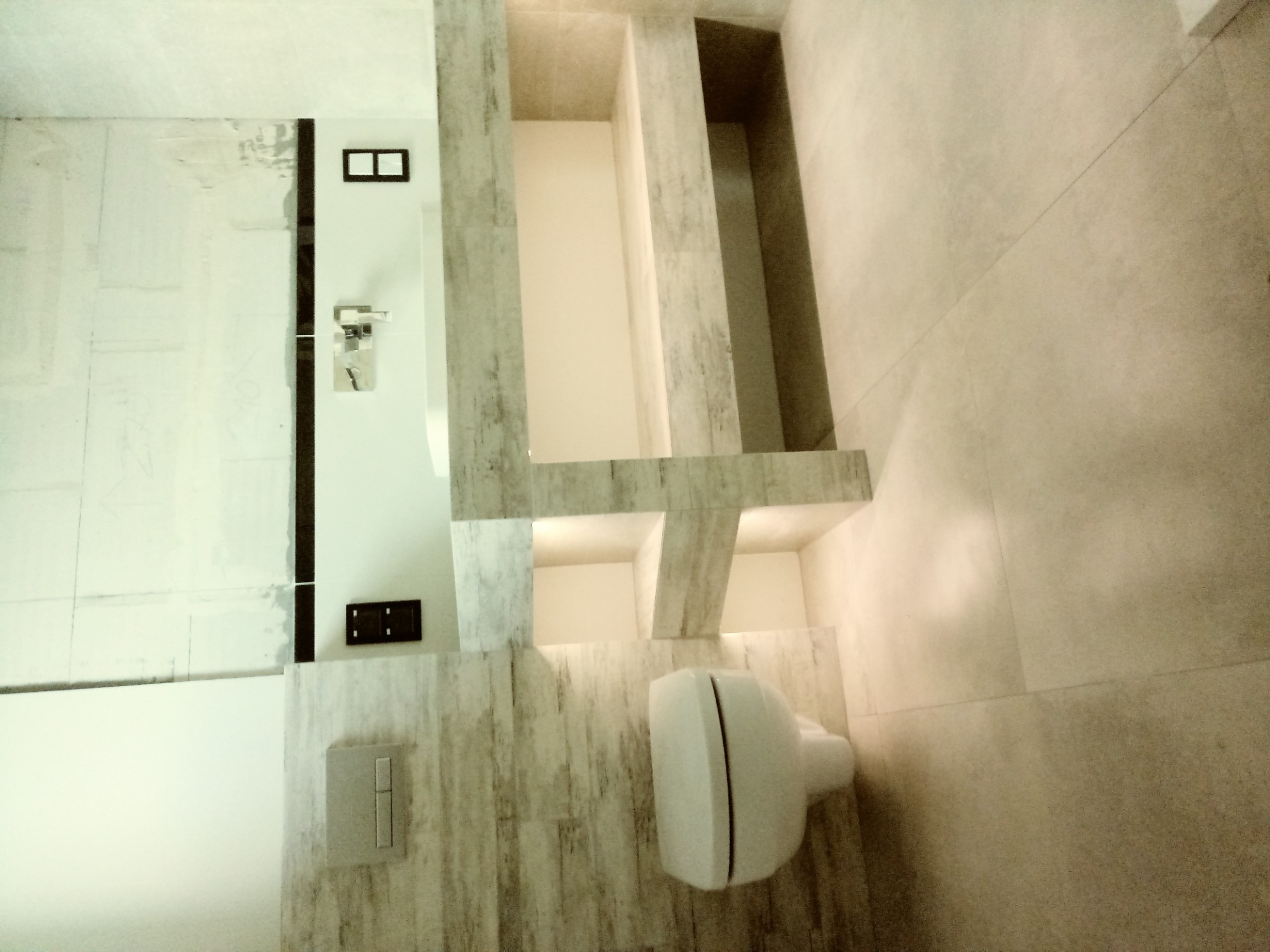 Wykończona łazienka w Dęblinie z toaletą wiszącą i zabudową z płytek imitujących drewno, widoczne wnęki ścienne.