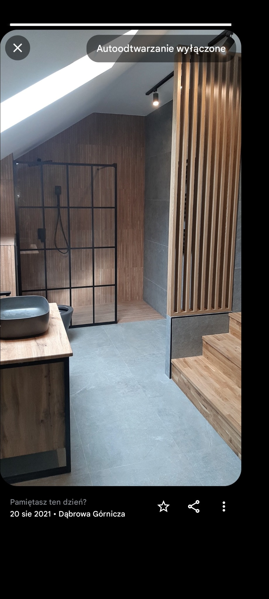 Nowoczesna łazienka na poddaszu z kabiną prysznicową typu loft, umywalką nablatową i drewnianymi elementami dekoracyjnymi, w tym ażurową ścianką działową i schodami.