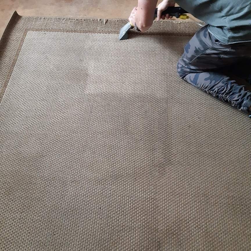 Czyszczenie beżowego dywanu z wyraźnym wzorem za pomocą parownicy, widoczne ślady po czyszczeniu.