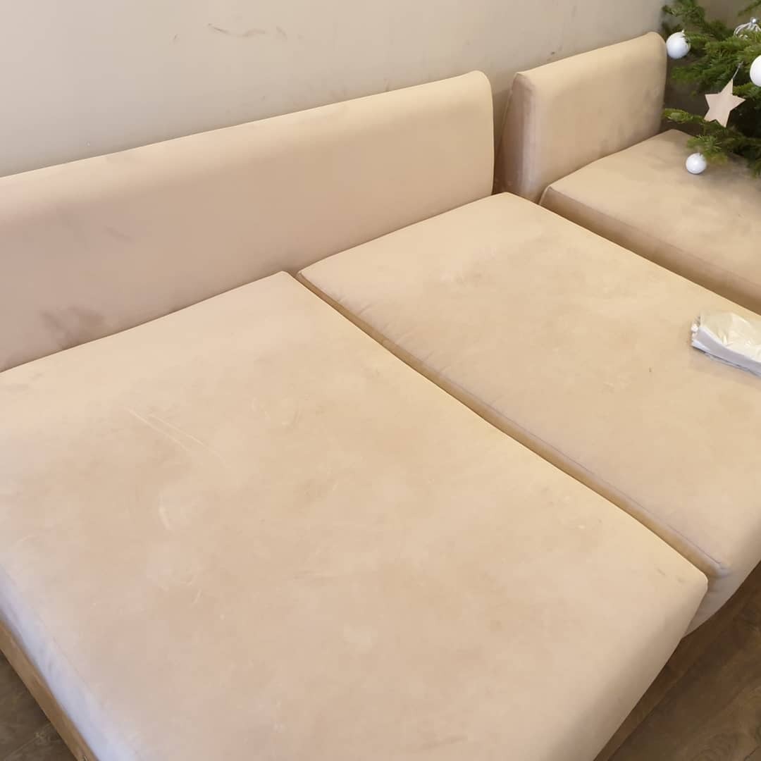 Jasna, modułowa kanapa z widocznymi plamami na siedzisku, obok choinka z białymi ozdobami.