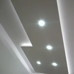 Nowoczesny sufit podwieszany z oświetleniem LED, widok z dołu, geometryczne kształty, jasne wnętrze.