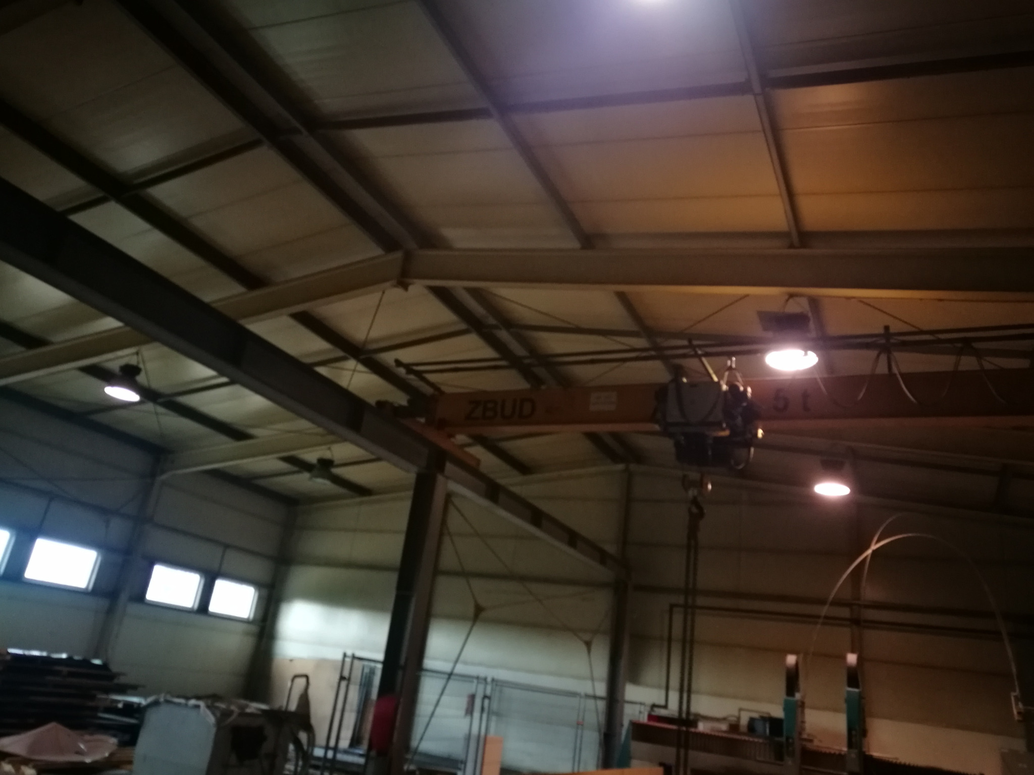 Wnętrze hali produkcyjnej w Krakowie z widoczną konstrukcją dachu, oświetleniem przemysłowym i suwnicą ZBUD 5t.