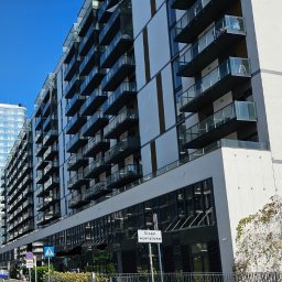 Lammos Floor - Nowoczesny budynek apartamentowy z licznymi balkonami i szklanymi balustradami, widoczny znak drogowy 'Droga wewnętrzna'.