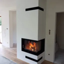 Nowoczesny narożny kominek z czarną ramą i paleniskiem, w trakcie montażu podłogi w jasnym wnętrzu.