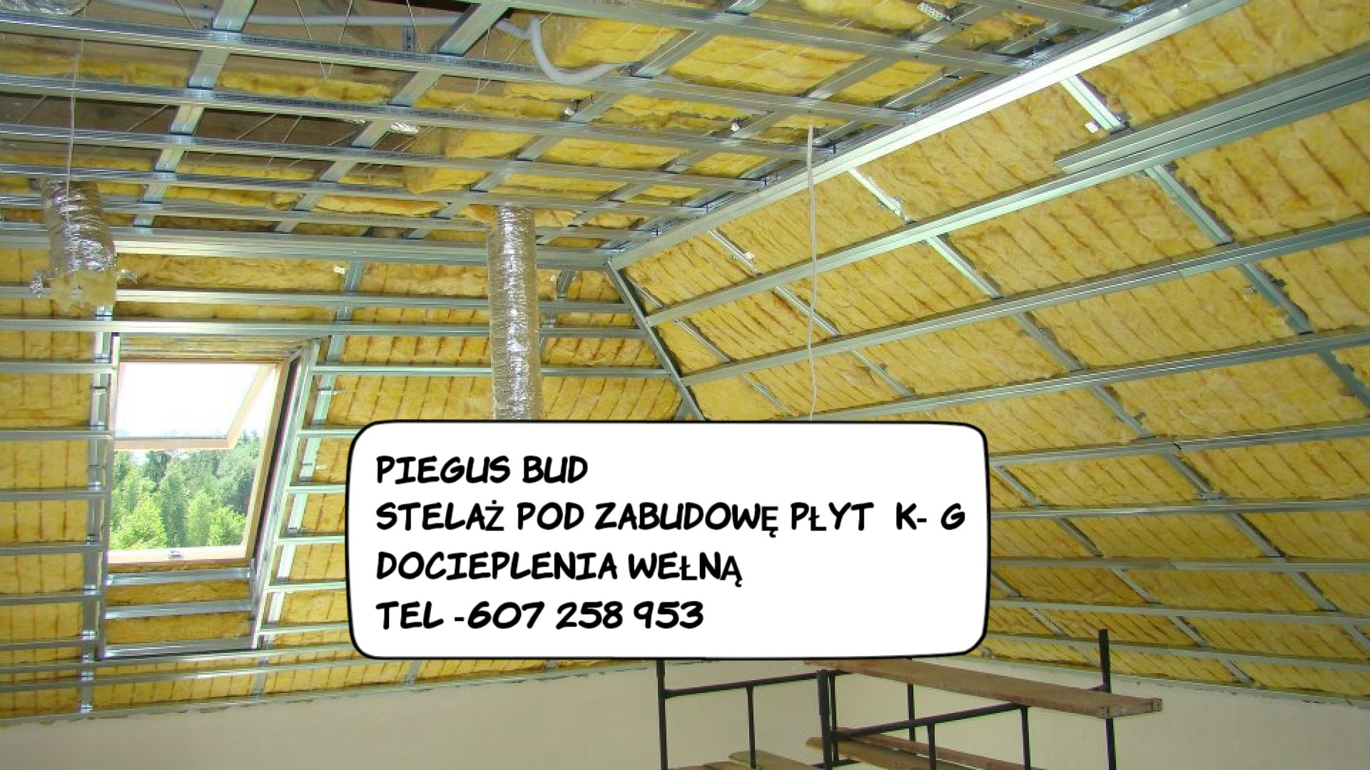 Skośny stelaż sufitowy z wełną mineralną, widok z dołu, częściowo widoczne rusztowanie i okno dachowe.