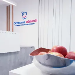 Recepcja gabinetu z logo 'Ochota na uśmiech' i misą pełną czerwonych jabłek na pierwszym planie.