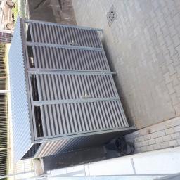 WELDER-SERWIS OLGA SIWIK - Metalowa konstrukcja z falistej blachy, prawdopodobnie osłona na pojemniki na śmieci, widoczna na tle kostki brukowej i zieleni.