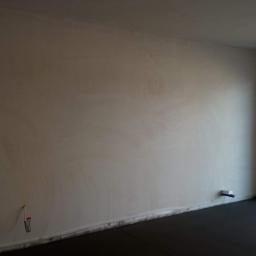 JM BUDINVEST - Świeżo otynkowane ściany w jasnym pomieszczeniu z widocznymi instalacjami elektrycznymi i hydraulicznymi przed wykończeniem.