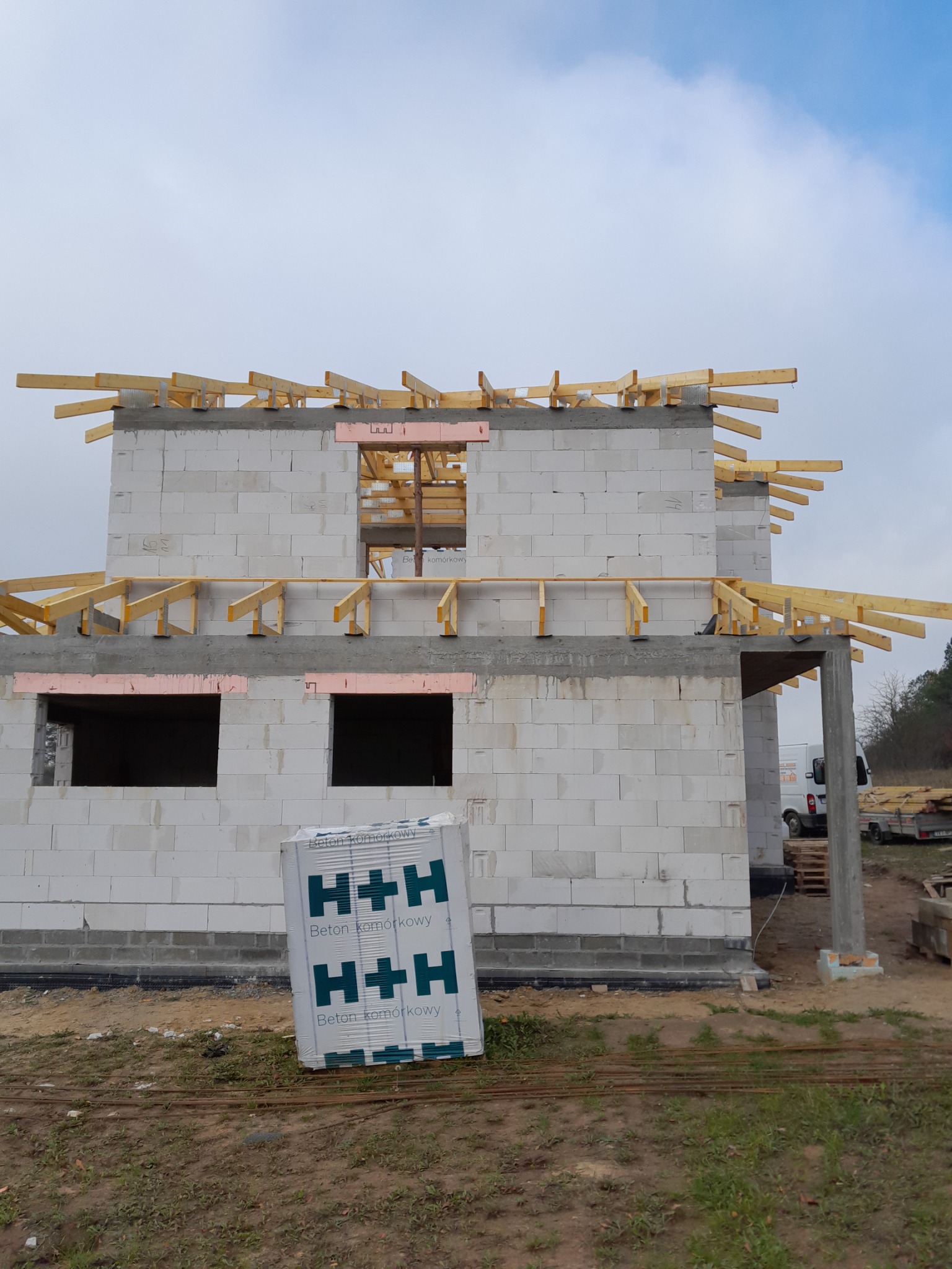 Budowa domu murowanego z betonu komórkowego H+H w Mniowie, widoczne drewniane elementy konstrukcji dachu i ściany w trakcie wznoszenia.