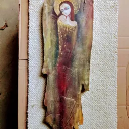 Ręcznie malowana, drewniana figurka anioła z aureolą, zawieszona na sznurku, leżąca na teksturowanej macie.