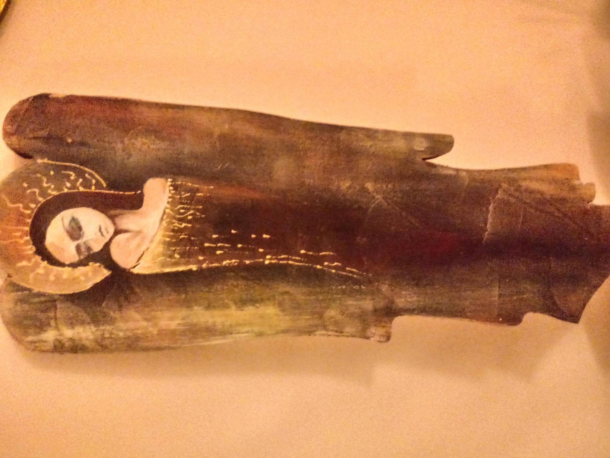 Ręcznie rzeźbiona drewniana figurka przedstawiająca śpiącą postać z aureolą, umieszczona na jasnym tle.