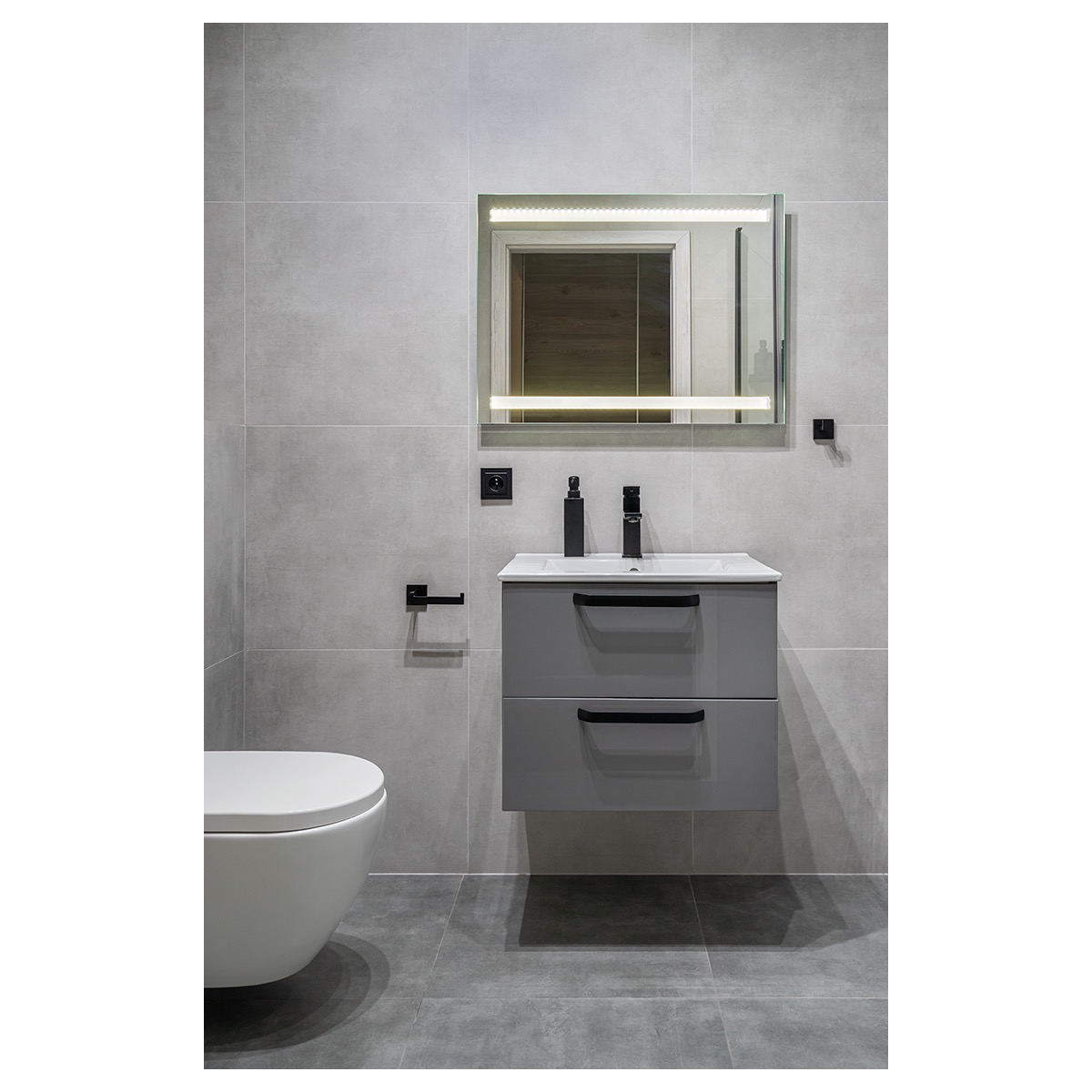 Szara łazienka z podwieszaną szafką umywalkową, podświetlanym lustrem i wiszącą toaletą, minimalistyczny styl.