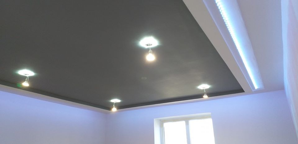 Czarny sufit podwieszany z punktowym oświetleniem i listwą LED w nowoczesnym wnętrzu.