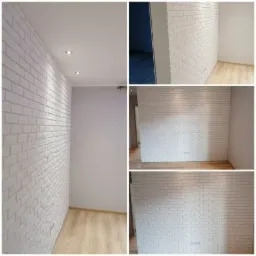 Wykończone wnętrze z białą ścianą z cegieł, widoczne halogenowe oświetlenie sufitowe i fragment parkietu, ściana pomalowana na szaro.