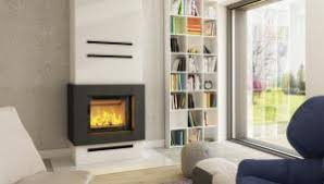 Nowoczesny wkład kominkowy w zabudowie z szarego betonu architektonicznego, z czarną obudową i poziomymi dekoracyjnymi listwami, na tle białej ściany z regałem na książki i dużym oknem.