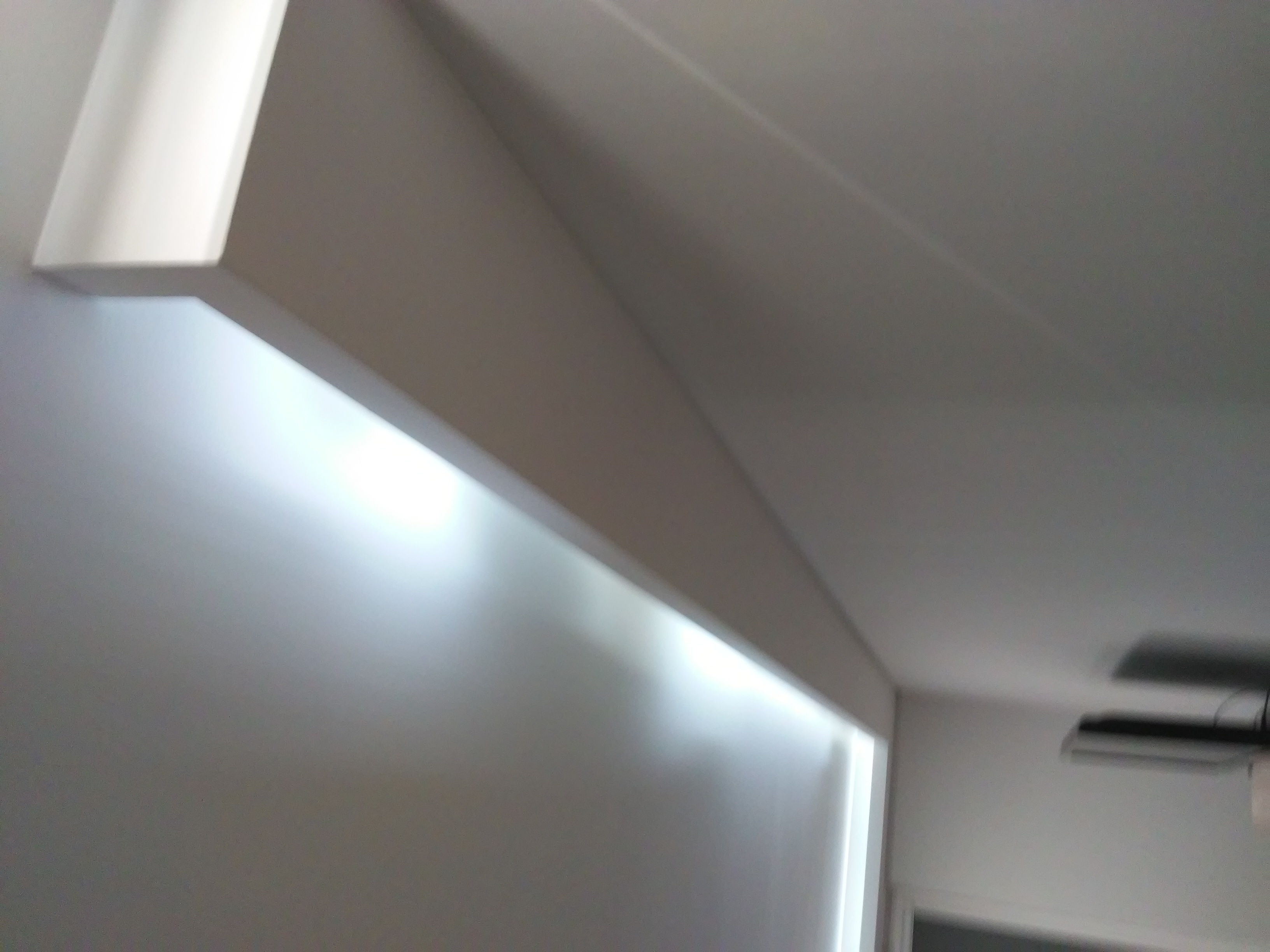 Nowoczesne oświetlenie LED ukryte za listwą przysufitową, tworzące subtelny efekt świetlny na ścianie i suficie.