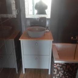 Prb Fakmet - Umywalka nablatowa w kolorze szarym na szafce z dwoma szufladami z bambusowym blatem, bateria chromowana, lustro w ozdobnej ramie, ciemne płytki na ścianie, mozaika na obudowie wanny, drewnopodobne...