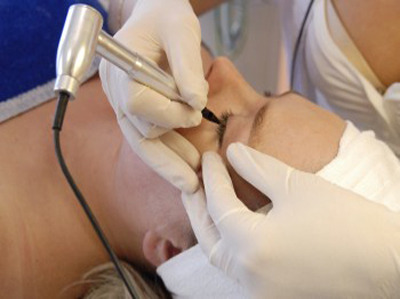 Precyzyjne wykonywanie permanentnego makijażu oka w Bydgoszczy, z użyciem specjalistycznego urządzenia i sterylnych rękawic.