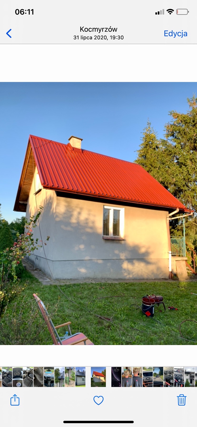 Dom z nowym, czerwonym dachem z blachy trapezowej, widoczne narzędzia malarskie na trawniku