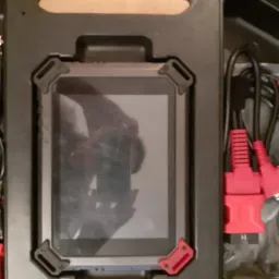 Diagnostic tablet with red connectors and black cables, stored in a protective case with a handle.