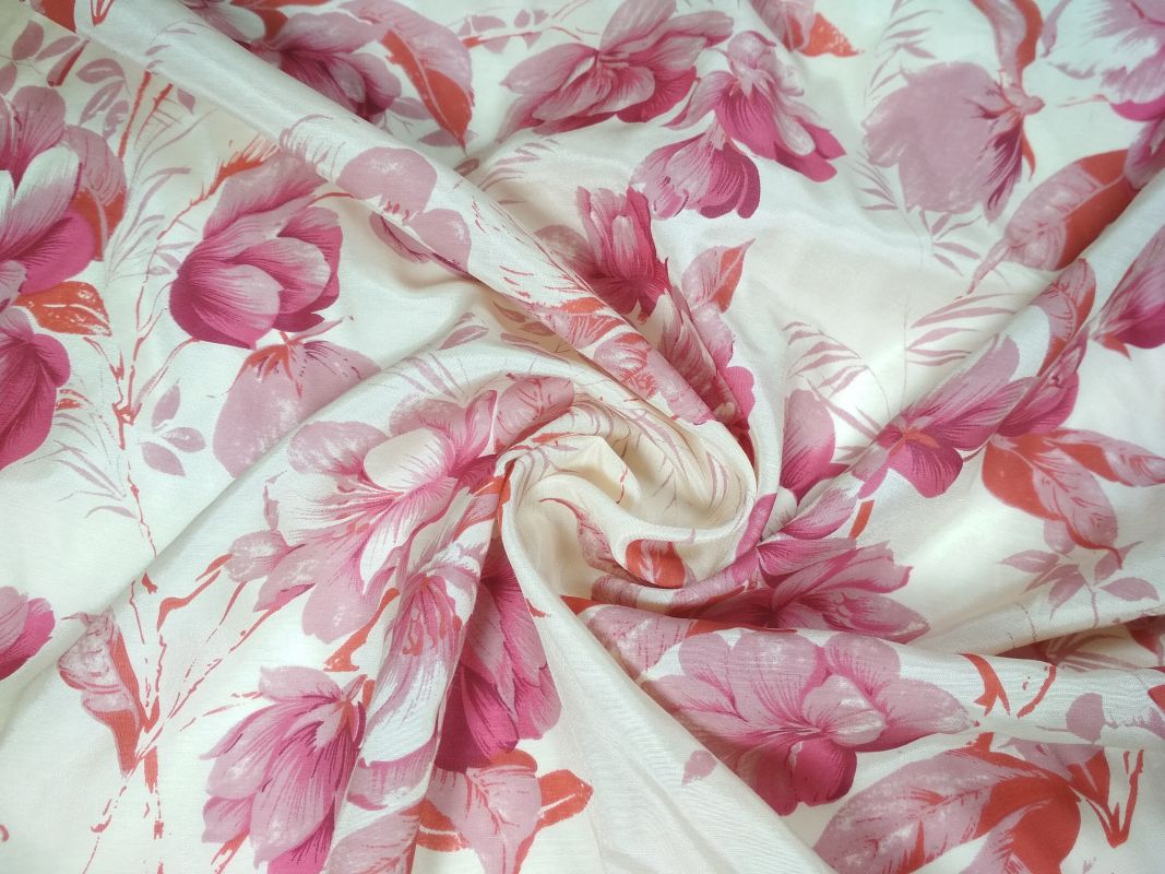Kremowa tkanina z wzorem różowych i czerwonych kwiatów, ułożona w miękkie fałdy.