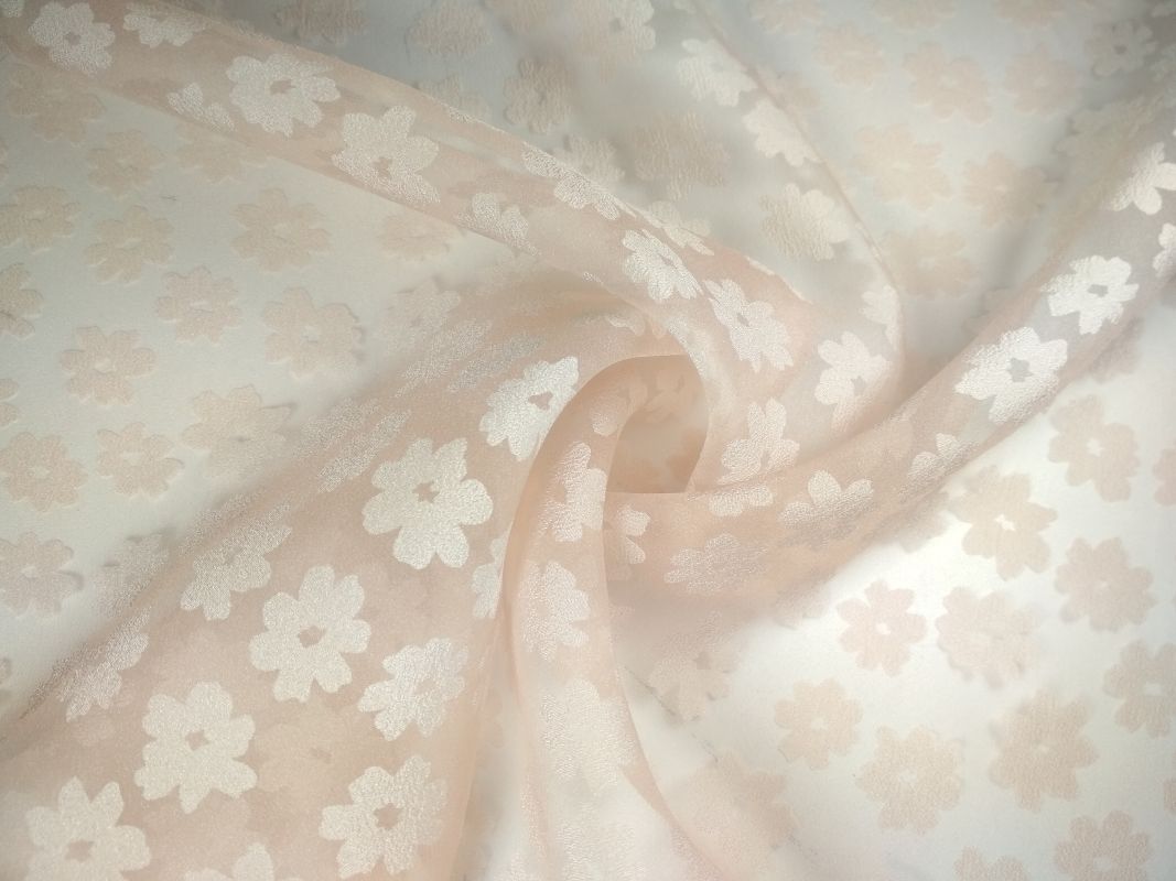 Delikatna, lekko transparentna tkanina w odcieniach kremu i beżu, z wytłaczanym wzorem drobnych kwiatów.