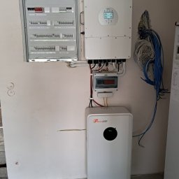 P.H.U. Eco-Constans - Kompletna instalacja fotowoltaiczna w pomieszczeniu: rozdzielnica, falownik Deye i akumulator Felicity ESS. Widoczne przewody i elementy montażowe.