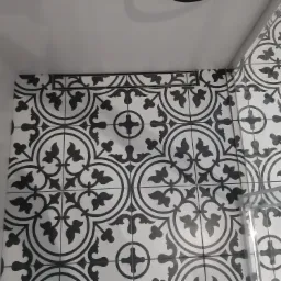 Fragment wykończonej łazienki z czarno-białymi płytkami podłogowymi w stylu retro i odpływem liniowym, widok z góry.