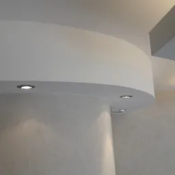 Nowoczesny sufit wielopoziomowy z zaokrąglonymi elementami i oświetleniem punktowym, wykończony gładzią o delikatnej fakturze.