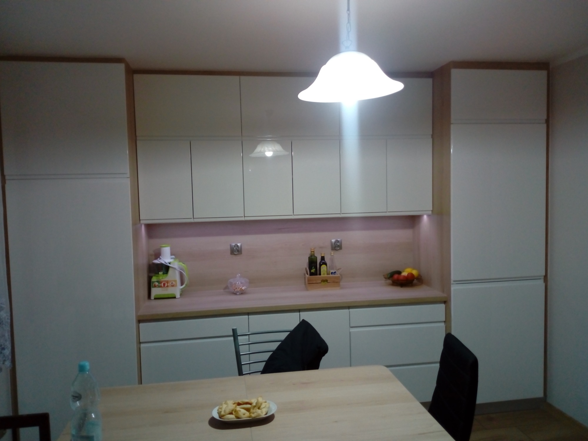 Kuchnia z frontami w białym połysku oraz blatem drewnopodobnym.