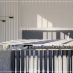 Wako Design - Kuchenna wyspa w stylu Art Deco z blatem oświetlonym promieniami słońca, na tle minimalistycznych białych szafek i dekoracyjnej lampy ściennej.