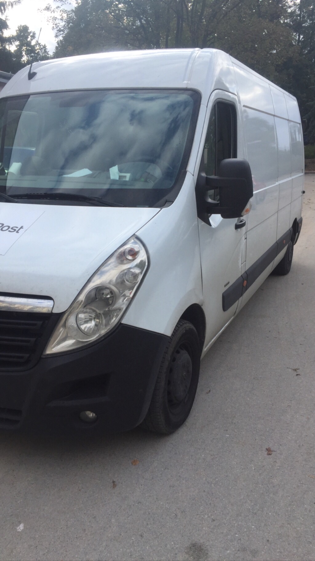 Biały bus dostawczy marki Opel zaparkowany na betonowym placu, widoczne logo firmy z boku, opony z czarnymi felgami.