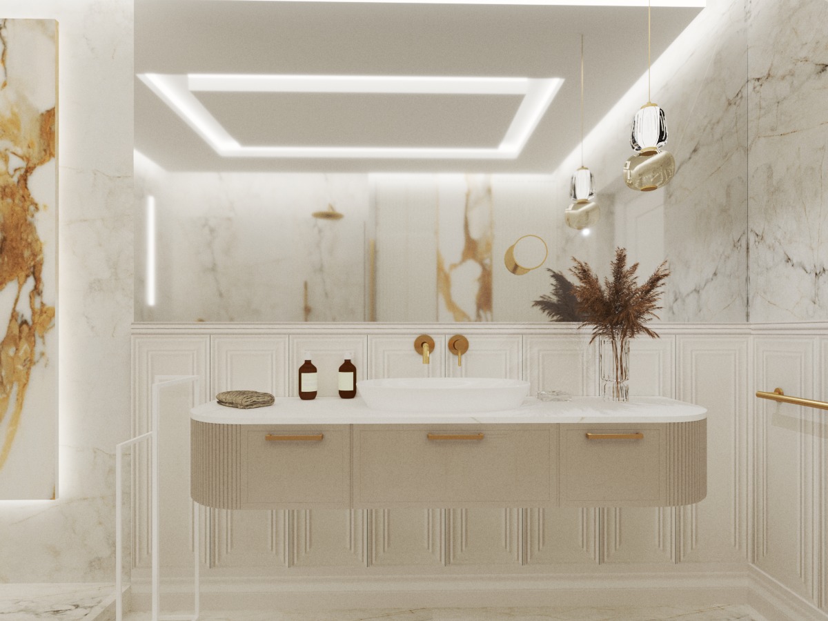 Elegancka łazienka z marmurowymi ścianami, beżową szafką pod umywalkę z trzema szufladami z delikatnymi złotymi uchwytami, okrągłe lustro, designerskie lampy wiszące i dekoracyjny bukiet w szklanym...