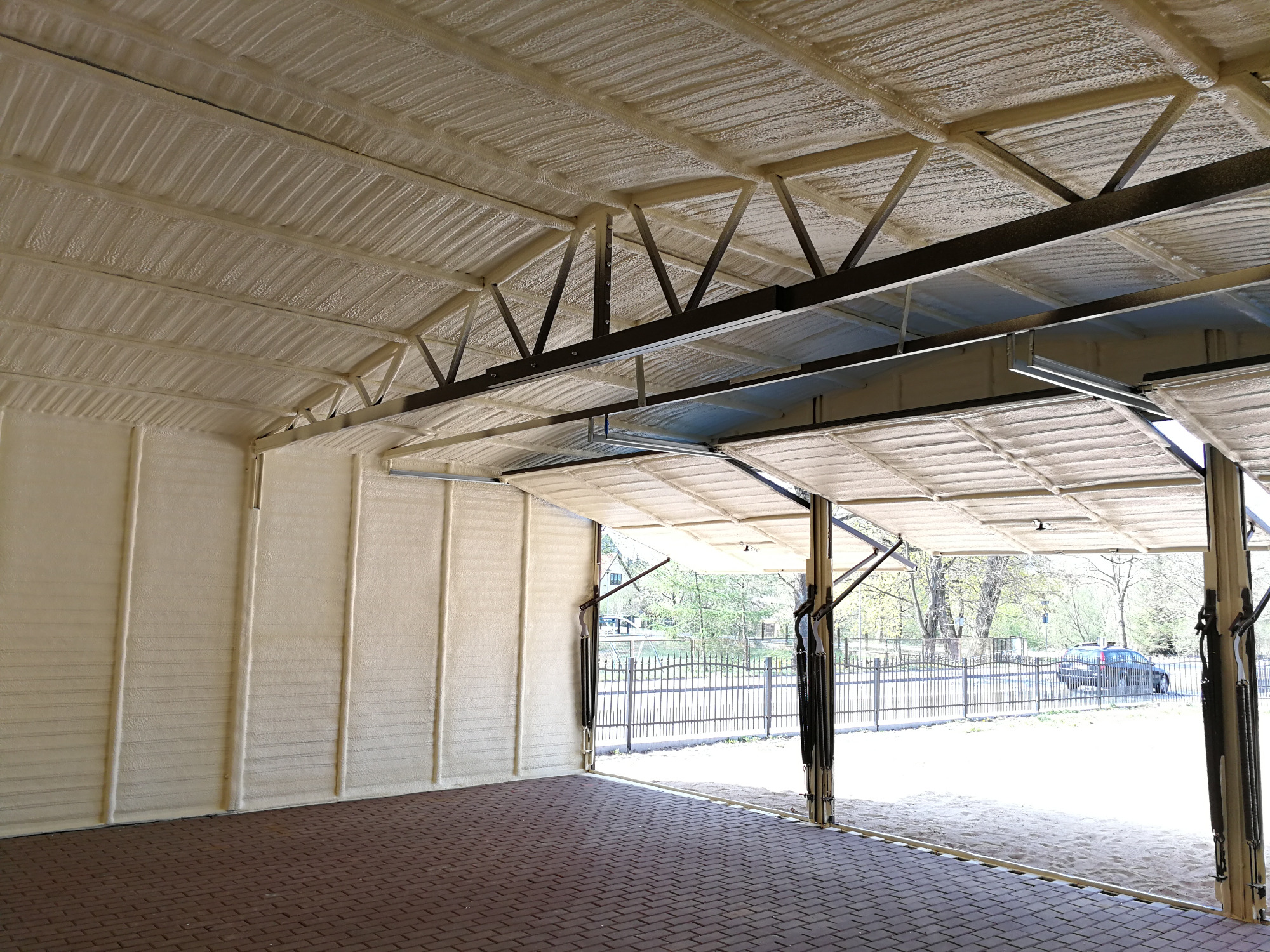 Wnętrze garażu w Toruniu po ociepleniu ścian i sufitu. Widoczna struktura naniesionej warstwy izolacyjnej.