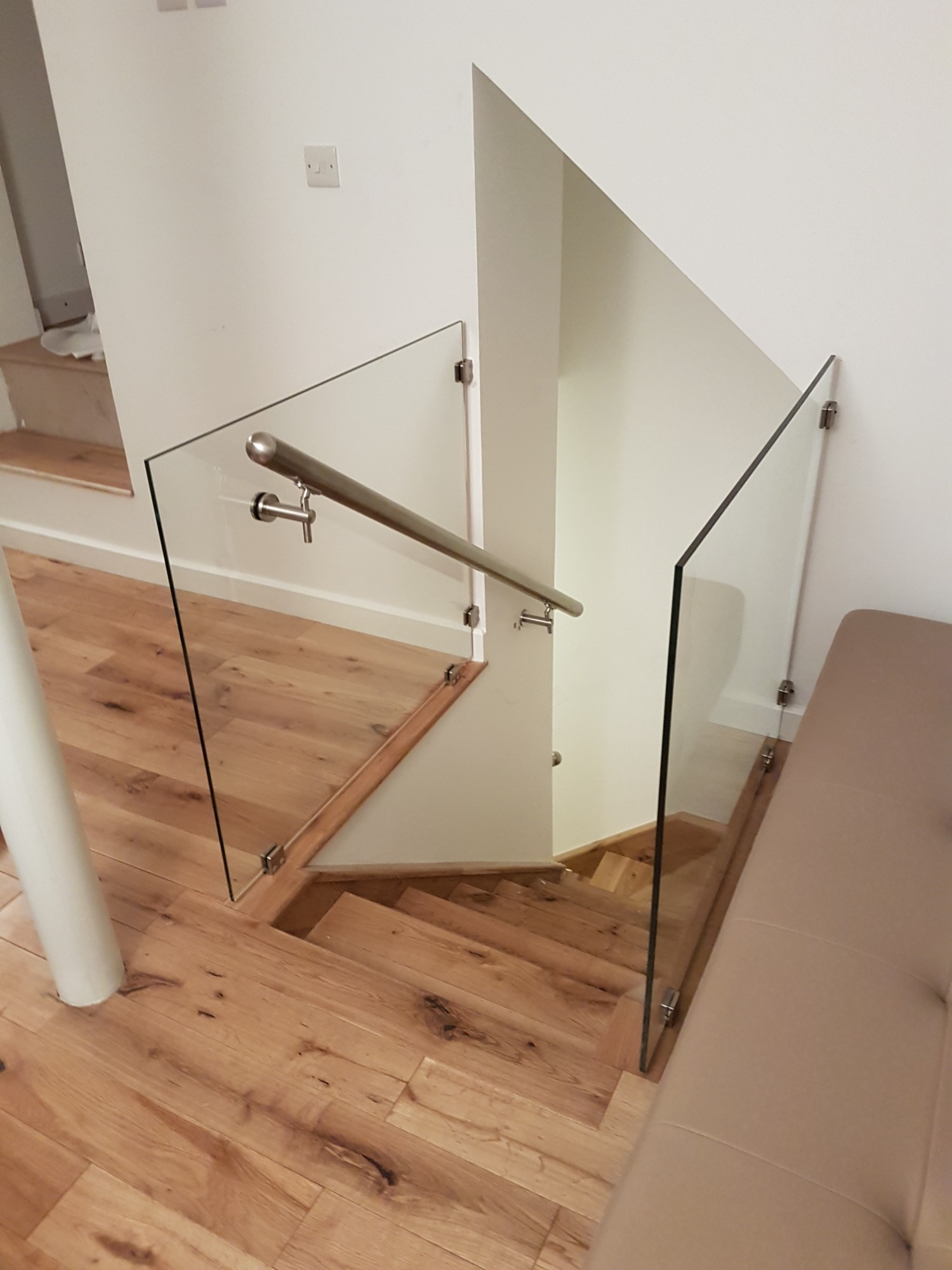 Szklana balustrada schodowa z drewnianymi schodami i podłogą, widok z góry, minimalistyczne wnętrze.